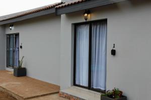 een wit huis met grote ramen en gordijnen bij Nini's guest units in Bloemfontein