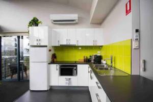 a kitchen with white appliances and a yellow wall at Panoramic views from your stunning 'Treehouse' in Grindelwald