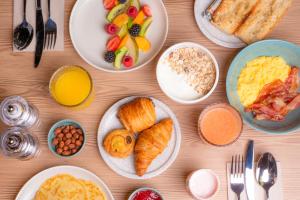 a wooden table with plates of breakfast food on it at Tribe Paris La Defense Esplanade in Courbevoie