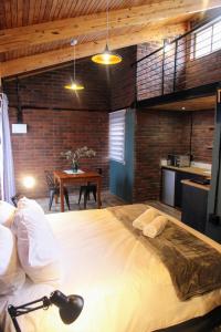 1 dormitorio con 1 cama grande y 1 mesa en Nini's guest units en Bloemfontein