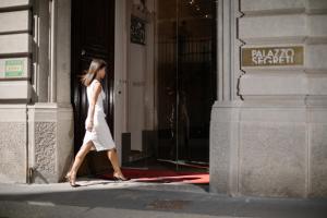Una mujer con un vestido blanco saliendo de un edificio en Palazzo Segreti, en Milán
