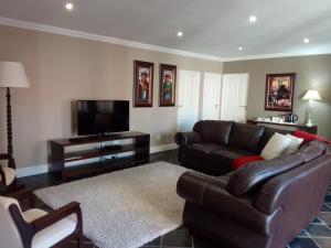 a living room with a couch and a flat screen tv at Waves Guest House in Jeffreys Bay