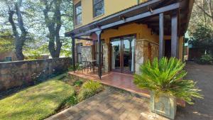 a house with a wooden porch with a patio at Catmandu in Dullstroom