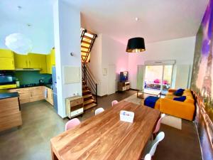 a living room with a wooden table and a kitchen at Magnifique VILLA avec jacuzzi au pied du STADE in Saint-Denis