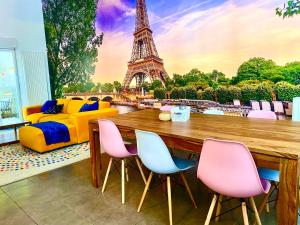 a room with a table and chairs and the eiffel tower at Magnifique VILLA avec jacuzzi au pied du STADE in Saint-Denis