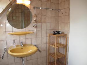 baño con lavabo amarillo y espejo en FeWo ONNO NORD151, en Norden