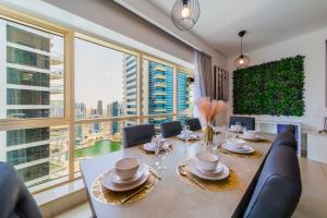 een eetkamer met een tafel en stoelen en grote ramen bij EDEN'S Homes & Villas - Royal Oceanic in Dubai