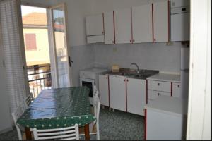 uma cozinha com armários brancos, uma mesa e um lavatório em Appartamento 6 em Ameglia