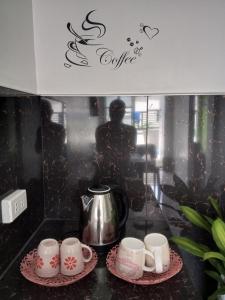 a set of coffee cups and a kettle on a counter at Budget Home in Iloilo Staycation At 8 Pax in Oton