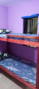 two bunk beds in a room with a purple wall at Budget Home in Iloilo Staycation At 8 Pax in Oton