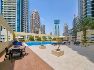 een patio met een zwembad en tafels, stoelen en gebouwen bij EDEN'S Homes & Villas - Royal Oceanic in Dubai
