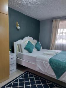 een slaapkamer met een wit bed met blauwe muren en een raam bij Parkview apartments in Nakuru