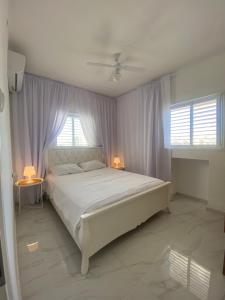 a bedroom with a large white bed with two lamps at Apartment Oskar Beach in Bat Yam