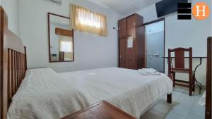 a bedroom with a white bed and a chair at El Hotelito in San José