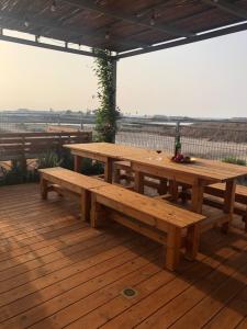 une table et des bancs en bois sur une terrasse en bois dans l'établissement Atlit Rooftop Glamping, à Atlit