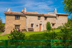 una antigua casa de piedra con una valla verde en Complex Rural Can Caubet, en Berga