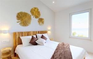 een slaapkamer met een bed met witte lakens en bruine kussens bij Gemütliche Villa mit Pool in Brela