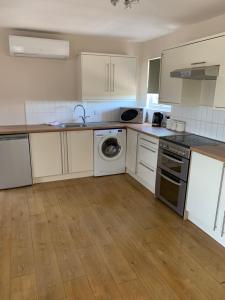 een keuken met witte kasten, een wastafel en een vaatwasser bij Arkenfield farm cabin in East Bridgford