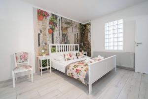 ein weißes Schlafzimmer mit einem Bett und einem Stuhl in der Unterkunft Villa Rose Garden in Nyíregyháza