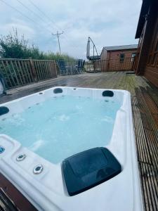 una bañera de hidromasaje en una terraza con parque infantil en Hedgerow Lodge with Hot Tub, en Malton