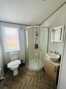 uma casa de banho com um chuveiro, um WC e um lavatório. em Hedgerow Lodge with Hot Tub em Malton