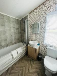 uma casa de banho com uma banheira, um lavatório e um WC. em Hedgerow Lodge with Hot Tub em Malton