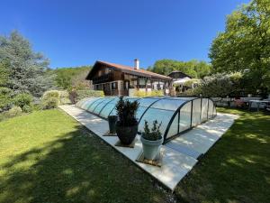 a house with a glass greenhouse in a yard at Le chalet des Pesettes in Thorens-Glières