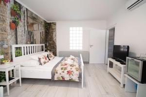1 dormitorio con 1 cama blanca y TV en Villa Rose Garden, en Nyíregyháza