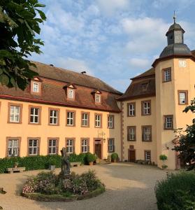 um grande edifício com uma estátua em frente em Private apartment in historic castle from 1608 with tenniscourt em Zeitlofs