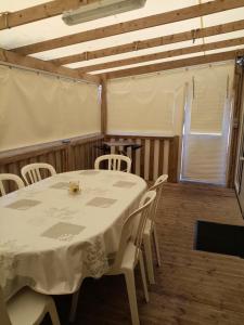 a dining room with a table and white chairs at camping les charmettes in Les Mathes