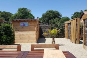 un jardín con un cobertizo de madera y 2 bancos en Le Chai de l'Océan - Studio, en Soulac-sur-Mer