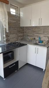 a kitchen with white cabinets and a sink and a stove at Cottage Teremok 7 people in Ureki