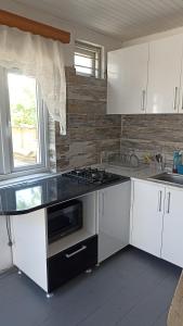 uma cozinha com armários brancos e um forno com placa de fogão em Cottage Teremok 7 people em Ureki