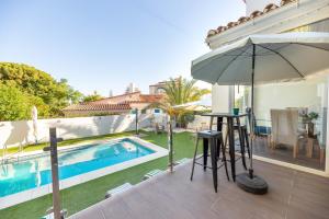 een patio met een tafel en een parasol naast een zwembad bij VB Guadalmedina 4BDR Renewed Villa in Benalmádena