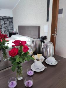 einen Tisch mit roten Rosen in einem Zimmer mit einem Bett in der Unterkunft Le Undici Rose Hotel in Viterbo