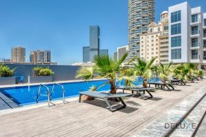 a pool on the roof of a building with benches at Lovely Studio in Pantheon Elysee JVC by Deluxe Holiday Homes in Dubai