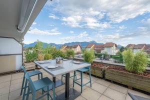 a table and chairs on a patio with a view of a city at Cabana & La Terrasse du Parmelan proche Annecy in Groisy