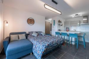 a bedroom with a blue bed and a kitchen at Cabana & La Terrasse du Parmelan proche Annecy in Groisy