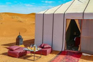 a tent in the desert with a table in front at Erg Chegaga Camp Excursions in Mhamid