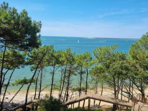 uma vista para uma praia com árvores e um passeio marítimo em Maison d’hôte neuve : T2 pour 4 voyageurs em Mios