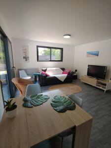 uma sala de estar com uma mesa e um sofá em Maison d’hôte neuve : T2 pour 4 voyageurs em Mios