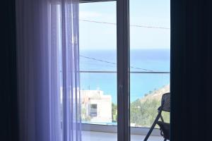 a window with a chair looking out at the ocean at SEA & LAKE VIEW VILLA in (( Kalive Gjoka ))