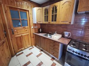 uma cozinha com armários de madeira, um lavatório e um fogão em Wspaniały Zakątek em Sędziszowa