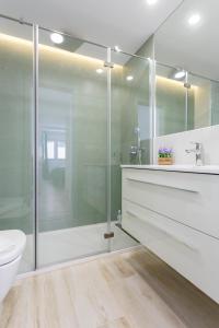 La salle de bains est pourvue d'une douche en verre et de toilettes. dans l'établissement ACQUARELA Family Home free parking by Cadiz4Rentals, à Cadix