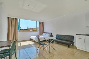 um quarto com uma cama, uma mesa e um sofá em Inn & Out Sandton Park em Joanesburgo