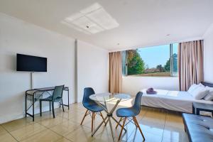 um quarto de hotel com uma cama, uma mesa e cadeiras em Inn & Out Sandton Park em Joanesburgo