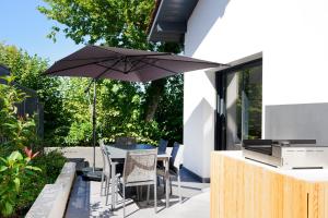 a patio with a table and chairs and an umbrella at Maison Aranea in Ascain