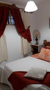 ラ・ファルダにあるFamilia Luchettiのベッドルーム1室(赤いカーテンと窓付きのベッド1台付)