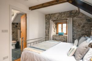 a bedroom with a bed and a stone wall at Stunning Converted Granary in Heart of St Davids in St. Davids