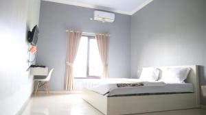 a white bedroom with a bed and a window at Cemara Guest House Syariah Kertajati 
